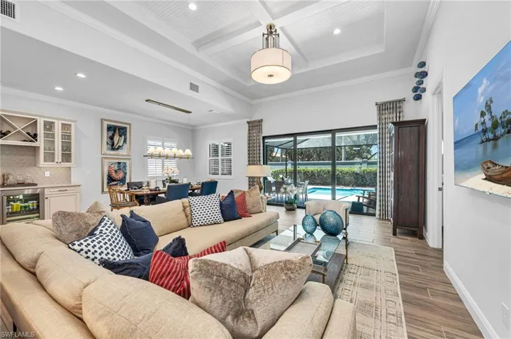 Living room with coffered ceiling, beverage cooler, a tray ceiling, crown molding, and beam ceiling