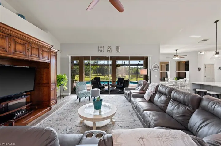 Living area featuring ceiling fan, lofted ceiling, visible vents, and light wood-style floors