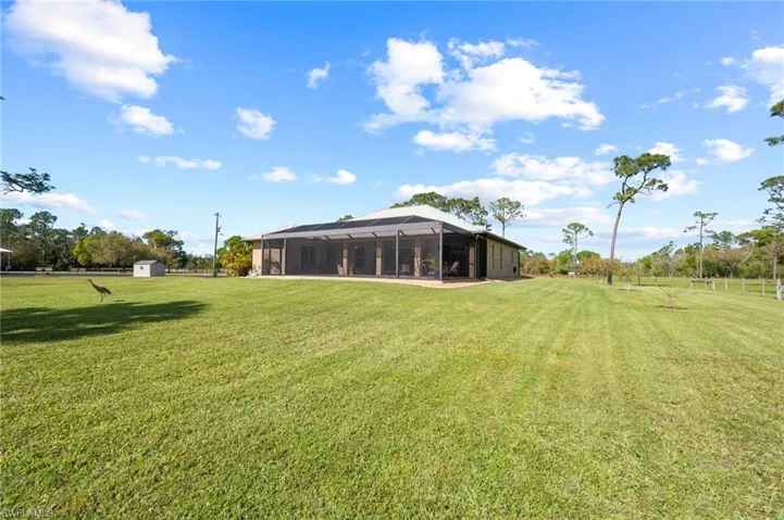 View of yard with glass enclosure, an outdoor structure, and a shed