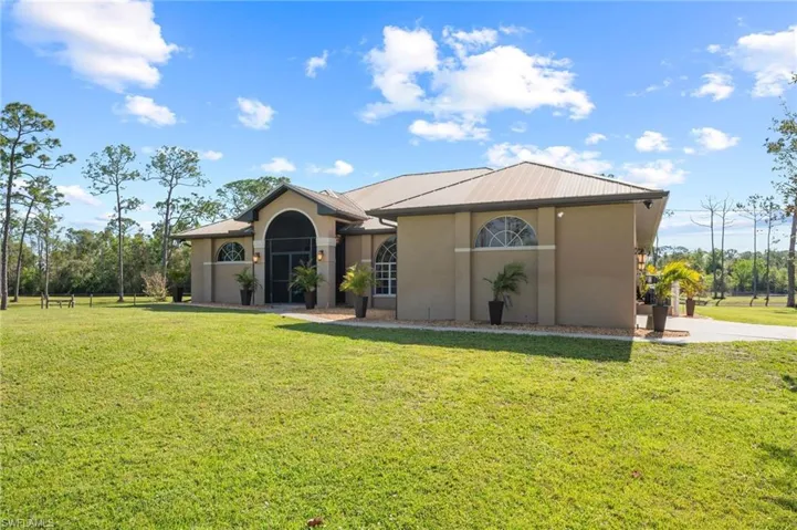 View of front of home with metal roof, a front lawn, and stucco siding