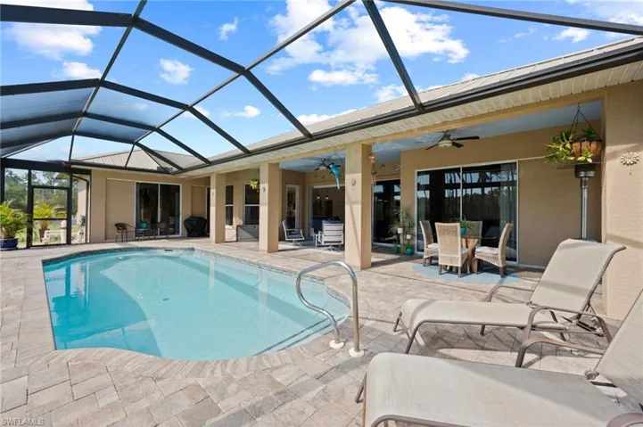 Outdoor pool featuring a lanai, ceiling fan, outdoor dining area, and a patio