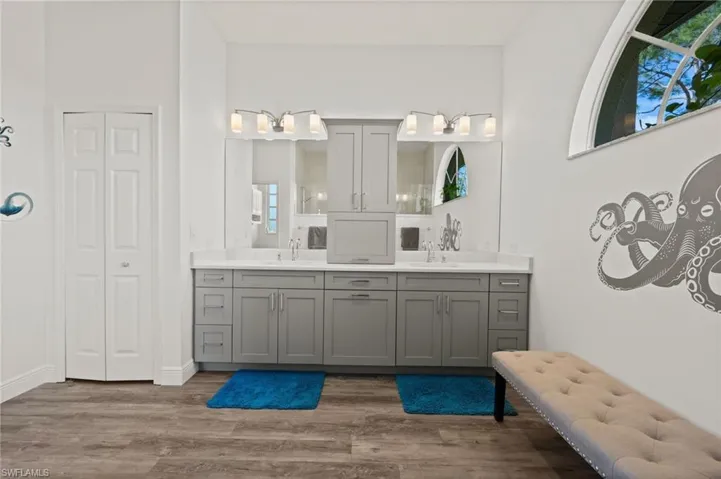 Full bath featuring a closet, double vanity, a sink, and wood finished floors