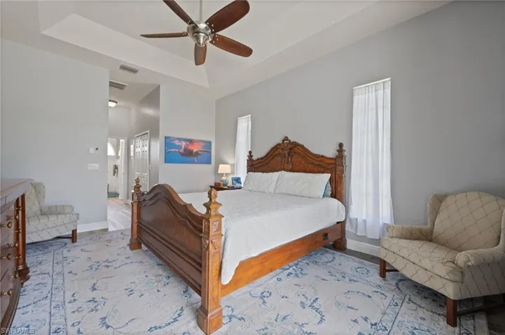 Bedroom with a raised ceiling, visible vents, and baseboards