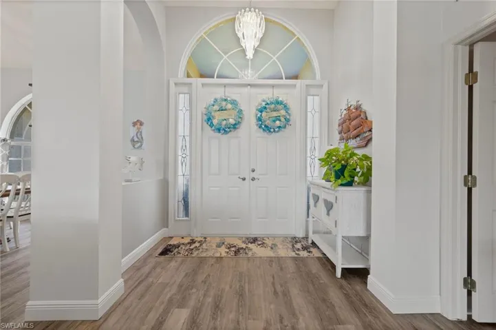 Entrance foyer featuring a chandelier, arched walkways, baseboards, and wood finished floors