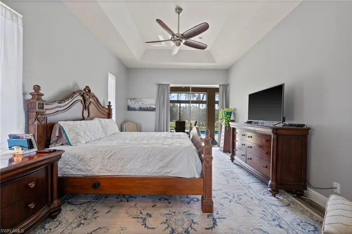 Bedroom with ceiling fan, access to outside, a raised ceiling, and baseboards