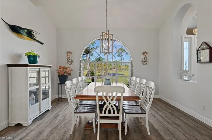 Dining area featuring arched walkways, a notable chandelier, baseboards, and wood finished floors