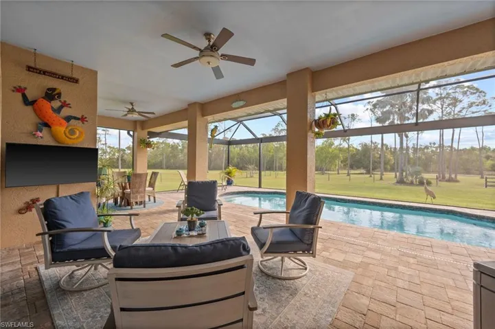 View of patio / terrace featuring a ceiling fan, outdoor dining area, glass enclosure, and an outdoor pool