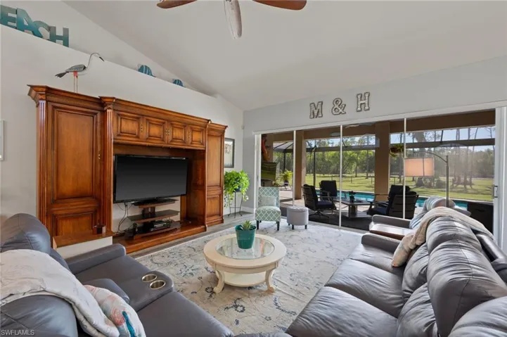 Living room with lofted ceiling, wood finished floors, and a ceiling fan
