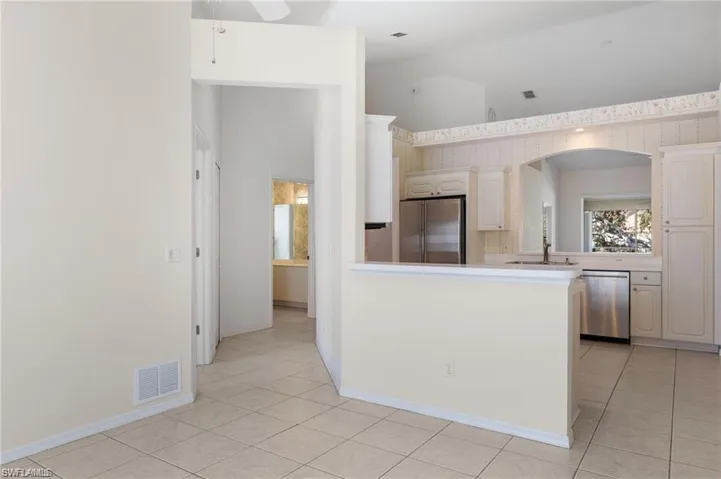 Kitchen featuring light tile patterned flooring, kitchen peninsula, ceiling fan, stainless steel appliances, and sink