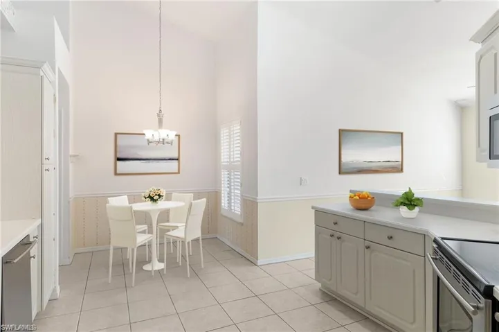 Kitchen with stove, pendant lighting, light tile patterned flooring, high vaulted ceiling, and a notable chandelier