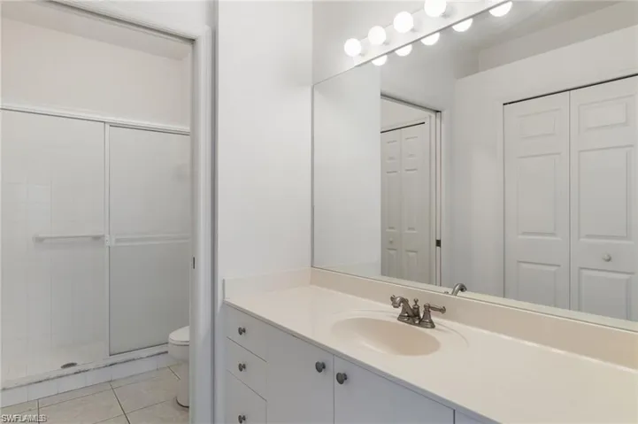 Bathroom featuring tile patterned flooring, toilet, vanity, and an enclosed shower