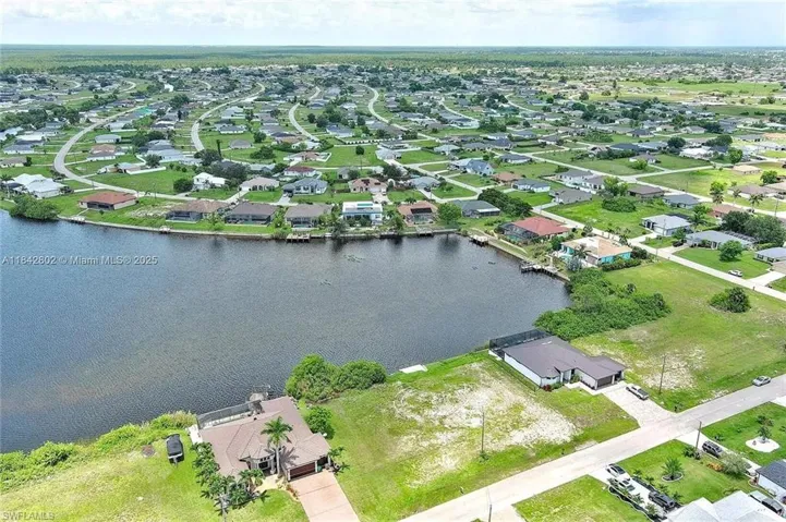 Aerial view of property and surrounding area with a large body of water and nearby suburban area
