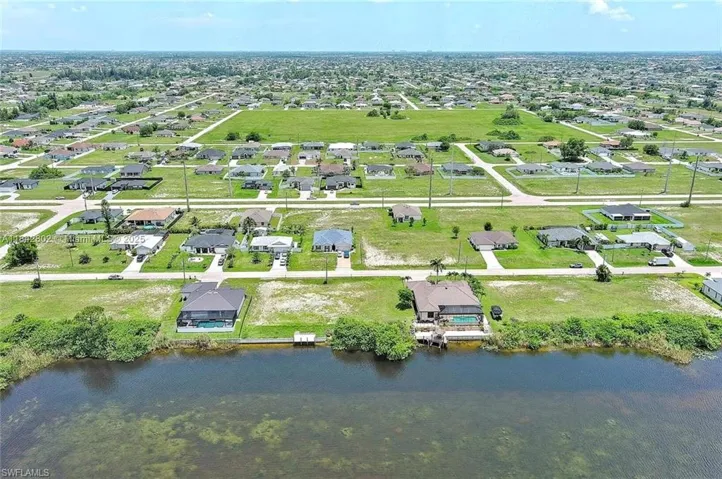 Aerial view of property and surrounding area with nearby suburban area and a large body of water