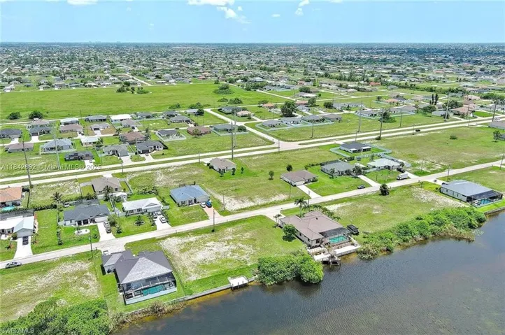 Aerial view of property and surrounding area featuring nearby suburban area and a nearby body of water