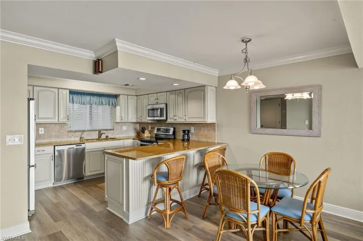 Kitchen with pendant lighting, appliances with stainless steel finishes, sink, backsplash, and kitchen peninsula