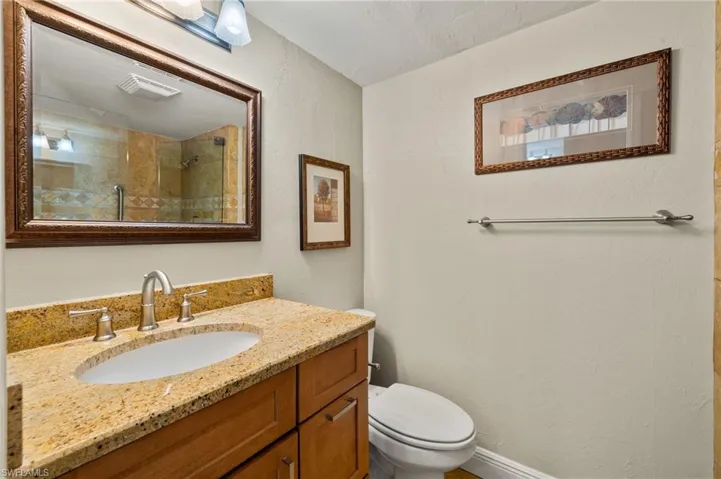 Bathroom with toilet, vanity, and tiled shower