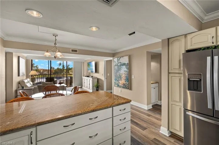 Kitchen with decorative light fixtures, stainless steel fridge with ice dispenser, a notable chandelier, and dark stone countertops