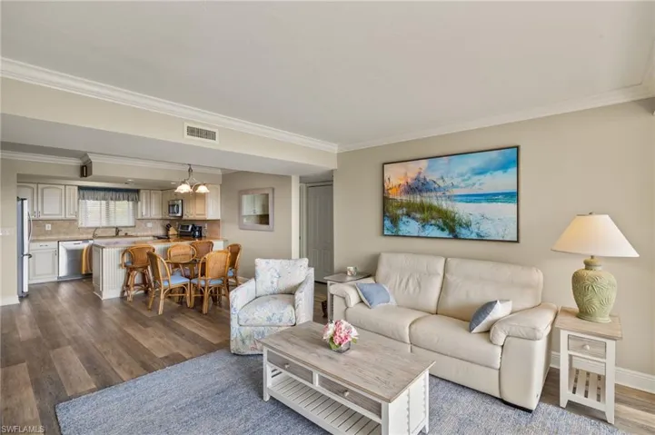 Living room featuring sink, ornamental molding, and hardwood / wood-style flooring