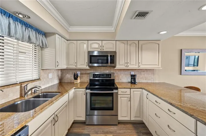Kitchen featuring light stone countertops, sink, crown molding, and stainless steel appliances