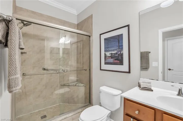Bathroom with oversized vanity, toilet, walk in shower, and crown molding