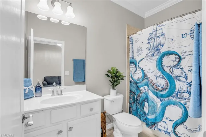 Bathroom with ornamental molding, oversized vanity, and toilet