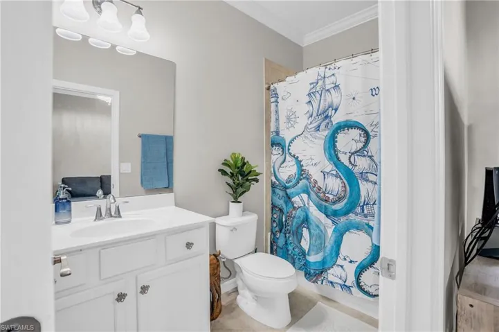 Bathroom with crown molding, tile flooring, toilet, and oversized vanity
