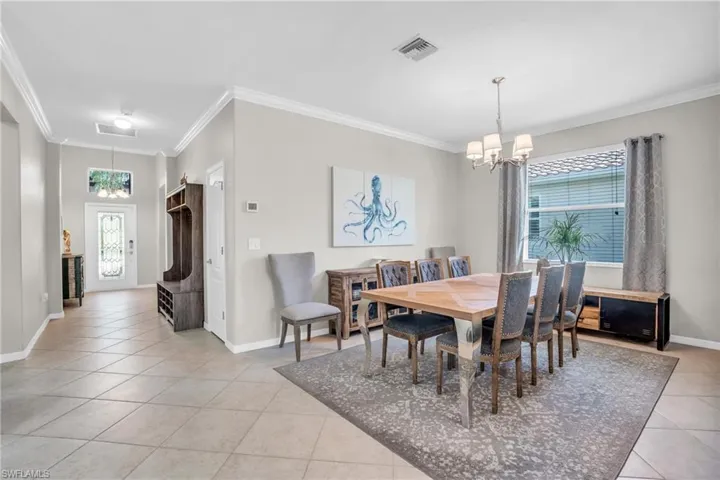 Tiled dining area featuring crown molding and a notable chandelier