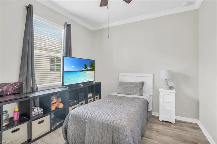 Bedroom featuring ornamental molding, light wood-type flooring, and ceiling fan