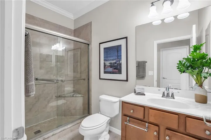 Bathroom featuring an enclosed shower, vanity, toilet, and crown molding