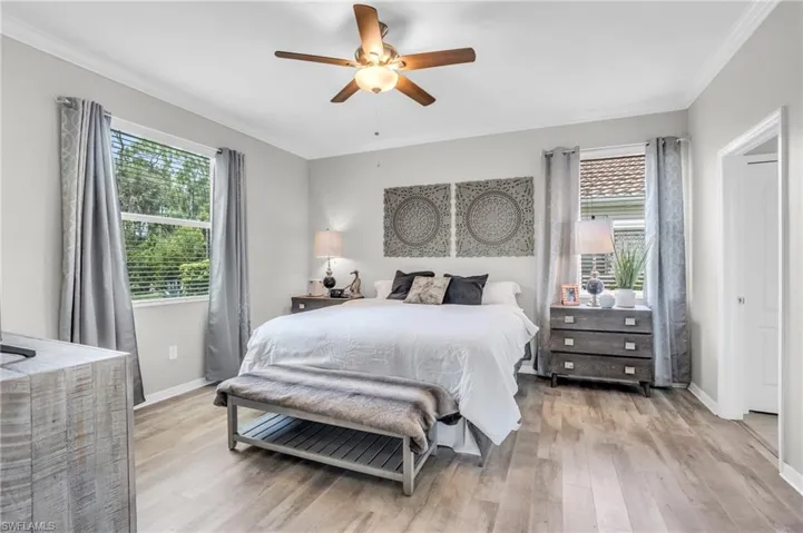 Bedroom with ceiling fan, light hardwood / wood-style floors, and crown molding