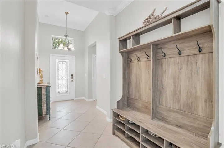 Mudroom featuring an inviting chandelier, ornamental molding, and light tile floors