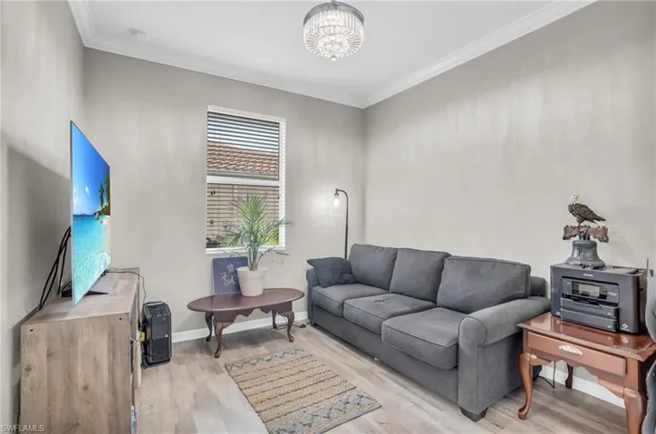 Living room with ornamental molding, an inviting chandelier, and light hardwood / wood-style flooring