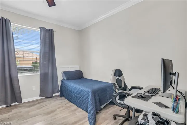 Bedroom featuring light hardwood / wood-style floors, ornamental molding, multiple windows, and ceiling fan