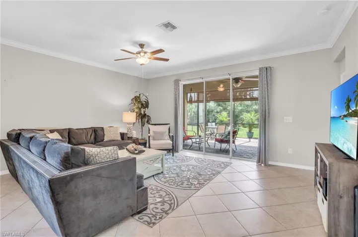 Living room with ceiling fan, ornamental molding, and light tile floors