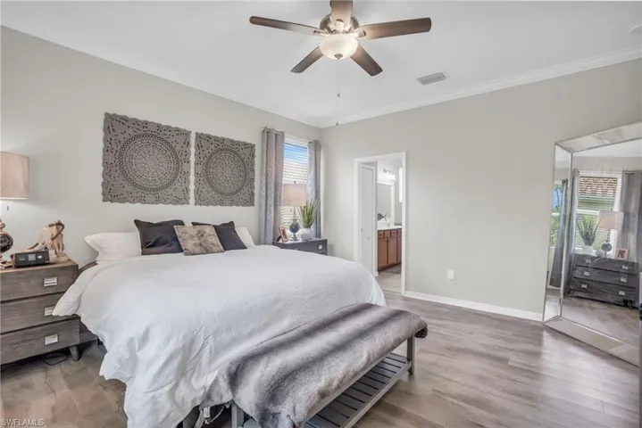Bedroom featuring crown molding, ensuite bathroom, ceiling fan, and hardwood / wood-style floors