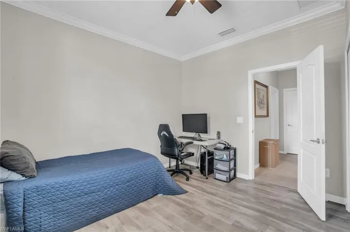 Bedroom with wood-type flooring, ceiling fan, and crown molding