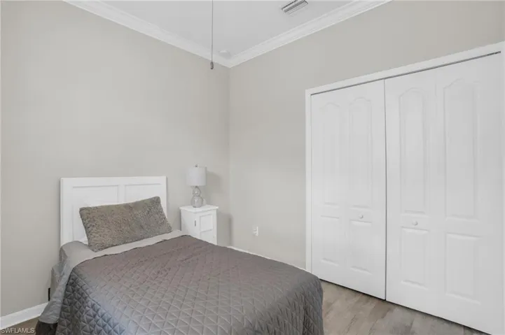 Unfurnished bedroom featuring crown molding, a closet, and hardwood / wood-style floors
