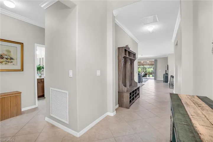 Hall with ornamental molding and light tile flooring