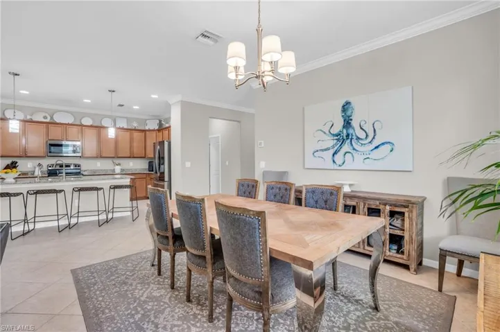 Dining room featuring crown molding, light tile floors, and an inviting chandelier