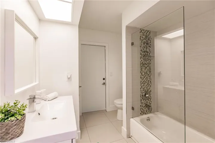 Full bathroom featuring a skylight, vanity, shower / tub combo with curtain, tile patterned flooring, and toilet