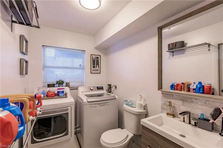 Bathroom with toilet, washing machine and dryer, backsplash, and vanity