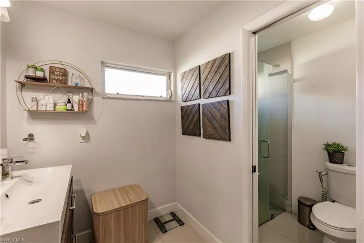 Bathroom featuring tile patterned floors, a shower with door, vanity, and toilet