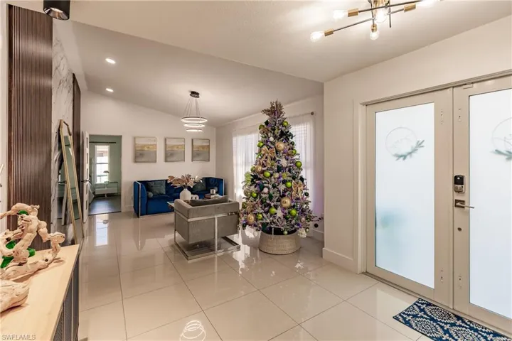 Tiled foyer entrance with plenty of natural light, a chandelier, and lofted ceiling