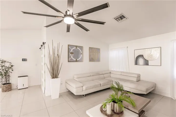 Tiled living room featuring ceiling fan and vaulted ceiling