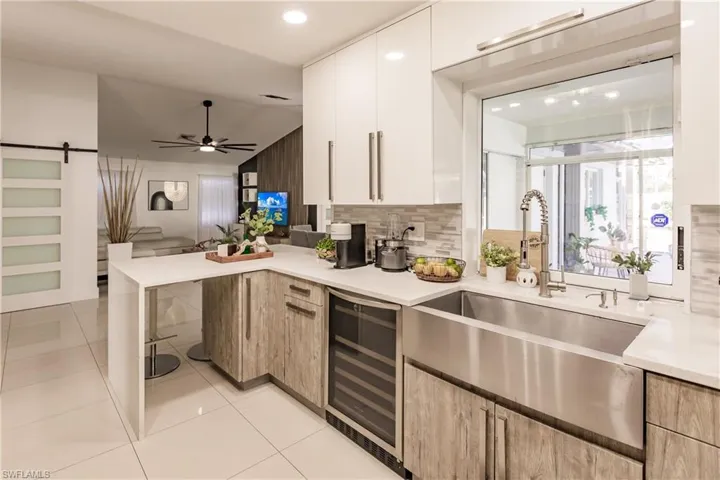 Kitchen with white cabinetry, beverage cooler, a barn door, lofted ceiling, and light tile patterned floors