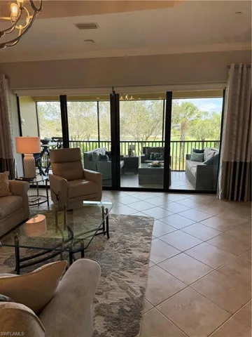 Living room featuring healthy amount of natural light, crown molding, light tile patterned floors, and a chandelier