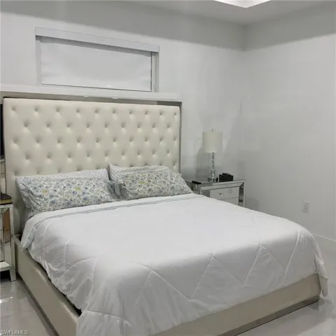 Bedroom featuring a high tufted headboard, recessed ceiling lighting, and a transom window with a roller shade