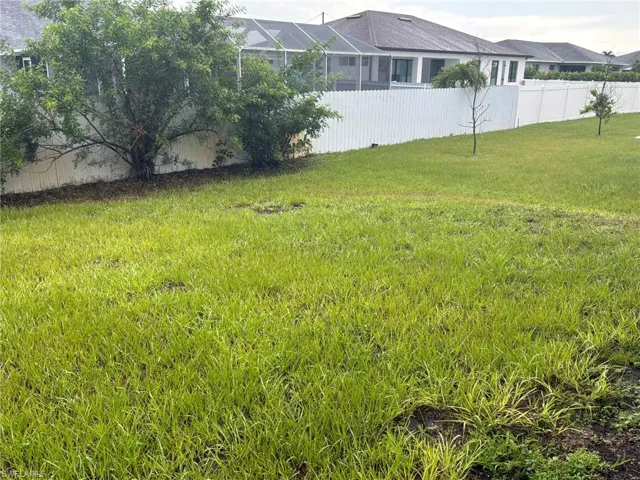 Expansive lawn area featuring a white privacy fence