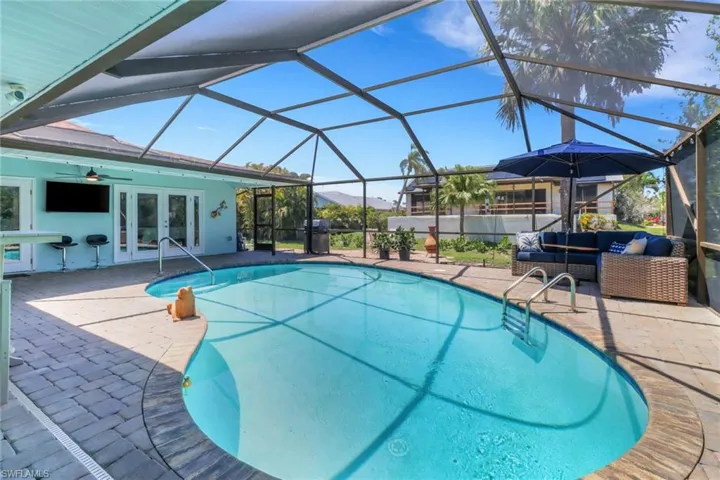 Swimming pool featuring french doors, a patio area, a sunroom, glass enclosure, and an outdoor hangout area