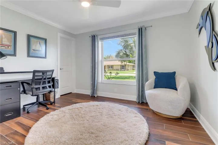 Home office featuring wood tiled floors, ornamental molding, and ceiling fan
